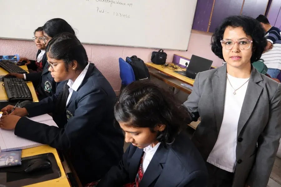 Students completing a career assessment on computers in a school computer lab, guided by a counsellor
